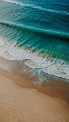 Obraz premium Aerial view of turquoise waves on a sandy beach surrounded by cliffs.