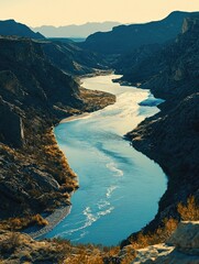 Obraz premium Nature's landscape featuring a river flowing in the desert with rocky cliffs, clear blue water, and a skyline that represents the Southwestern terrain.