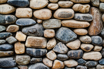 A close up of a rock wall with a variety of different sized rocks. The wall is made of cement and the rocks are scattered all over it. The image has a rugged and natural feel to it