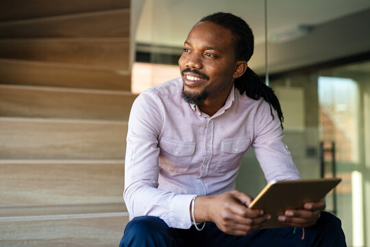 Relaxed smiling african american man holding digital tablet computer using apps