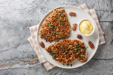 Crispy chicken in pecan crust with spicy sauce close-up in a plate on the table. horizontal top view from above