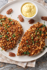 Chicken cutlets are breaded in a delicious pecan crust and baked until perfectly crispy close-up in a plate on the table. Vertical top view from above