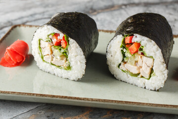 Burrito sushi or Sushirrito with grilled chicken, rice, cream cheese, cucumber, bell pepper, nori and lettuce close-up in a plate on the table. horizontal