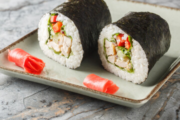 Chicken Sushirrito with rice, cream cheese, cucumber, bell pepper, nori and lettuce close-up in a plate on the table. horizontal