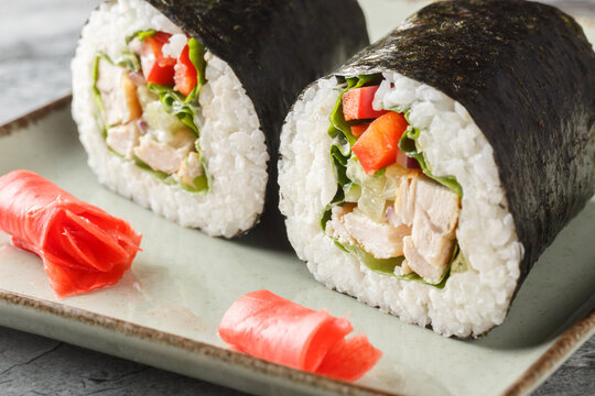 Delicious sushi burrito with rice, chicken, cream cheese, vegetables, nori and lettuce close-up in a plate on the table. horizontal