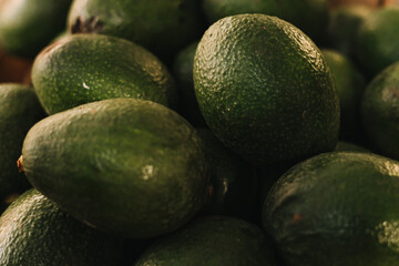 Freshly harvested avocados grouped together in a tight frame, showcasing their vibrant green color. Shopping At Farmers Market Stall. Close up. Part of the series