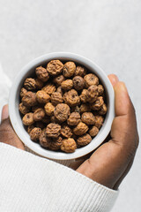 Overhead view of dried tiger nuts in a white bowl. top view of Yellow Nutsedge in a bowl