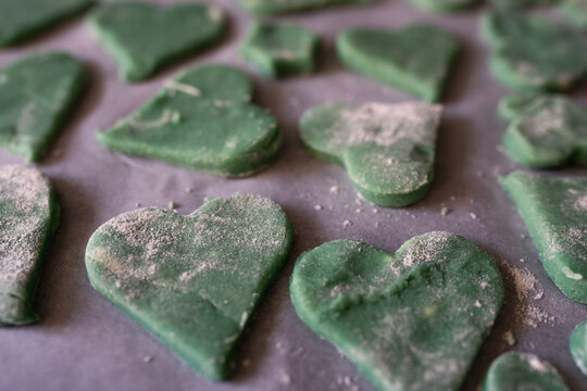 Green heart-shaped cookies decorated with love for a fun family baking activity. Family baking moments with kids.