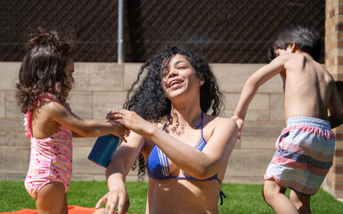 Daughter and son applying sunscreen lotion to her mother before swimming in the pool