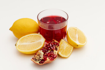 pomegranate and lemon next to a glass of pomegranate juice
