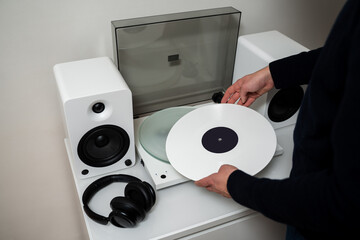 Musician places a white vinyl record into a turntable to enjoy soundtracks with Hi-Fi and LP. White...