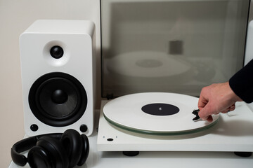 Musician places a white vinyl record into a turntable to enjoy soundtracks with Hi-Fi and LP. White...