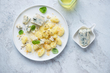 Plate of italian gnocchi served with blue cheese, horizontal shot on a white stone background, above view