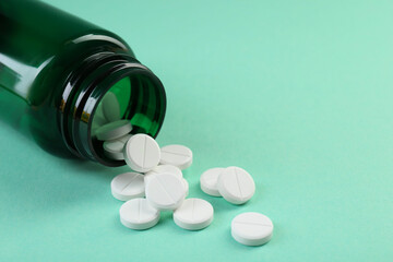 Medical bottle with antibiotic pills on turquoise background, closeup. Space for text