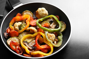 Frying pan with vegetables and mushrooms on stove, closeup