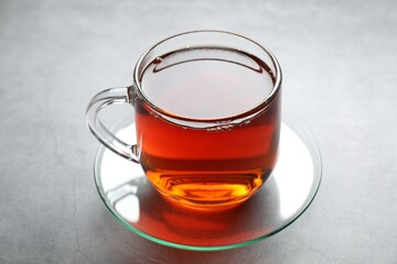 Refreshing black tea in cup on grey textured table, closeup