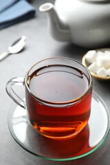 Refreshing black tea in cup on grey table, closeup