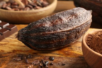 Cocoa pod, beans, powder and chocolate on wooden table, closeup
