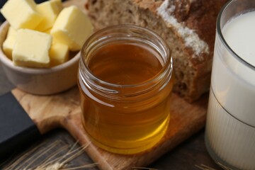 Sweet honey, butter, bread and milk on wooden table, closeup