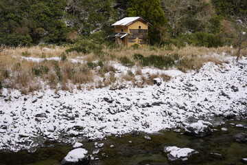 雪の残る川原と廃屋
