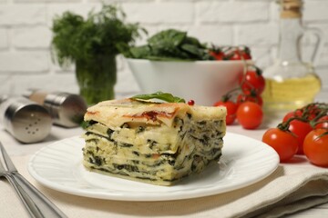 Piece of delicious spinach lasagne served on white table, closeup