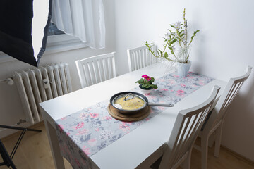 Kitchen table and breakfast ready - egg omelette. In the background a flash for taking pictures