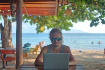 Young caucasian male working remotely on laptop at tropical beach