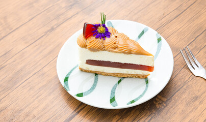 A close-up of  served Cheesecake decorated with flowers on a ceramic plate with a latte on a rustic wooden table in a cozy cafe setting.