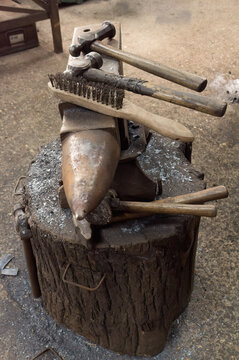 Set of blacksmiths tools; anvil, hammers, brush, resting on an anvil in a forge.