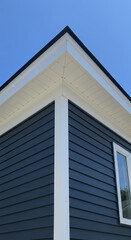 Fototapeta premium Modern Home Exterior: Dark Blue Siding, White Trim, and Blue Sky - A Stylish Architectural Design Detail