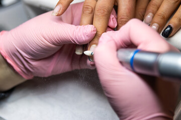 Nail technician using electric file during manicure