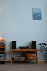 Modern minimalist home entertainment setup featuring a vintage vinyl record player, speakers, and organized shelving unit against a blue wall with decor elements
