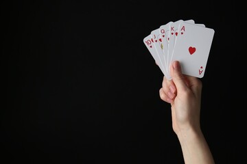 Obraz premium Woman with playing cards against black background, closeup