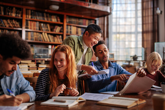 Joyful students study together in library.