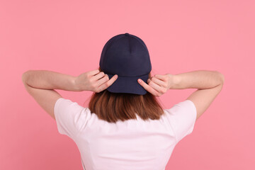 Woman in stylish baseball cap on pink background, back view. Mockup for design