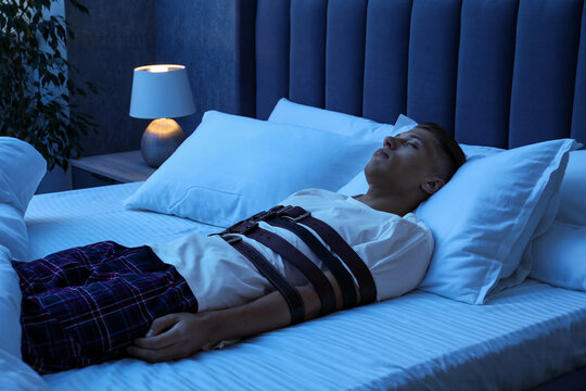 Sleepwalker fastened with belts lying on bed