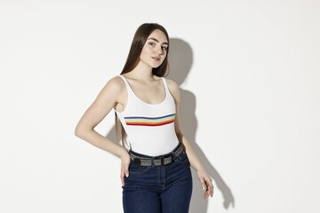 Beautiful young woman in stylish jeans on light background