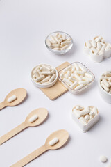 White pills and tablets in small plates on a white background, top view. Many vitamins, minerals and organic food supplements in forms of pills. Healthy lifestyle. Beautiful composition with pills.