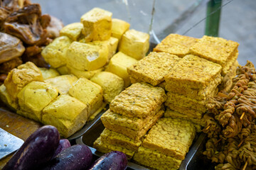  Tofu and tempeh, popular Indonesian ingredients, on display at a market or food stall.  Ready for cooking