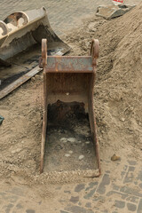 rusty steel shovel bucket stands outside on the sand