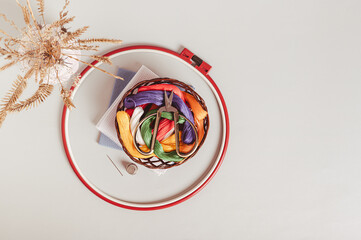 Scissors on basket with colored embroidery threads in hoops on gray background top view