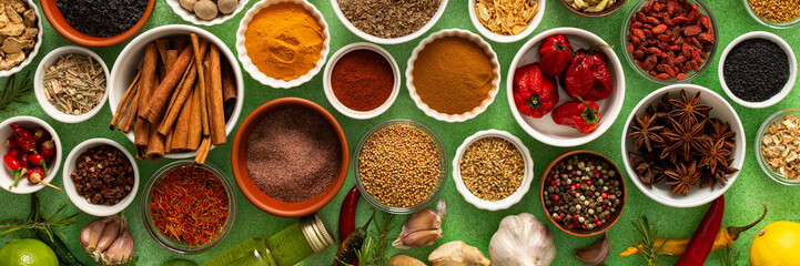 Fresh, multicolored spices and herbs set against a gentle green background, creating a vivid, fragrant display perfect for food inspiration, banner