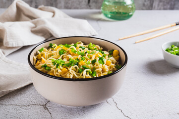Instant noodles with corn and green onions in a bowl on the table