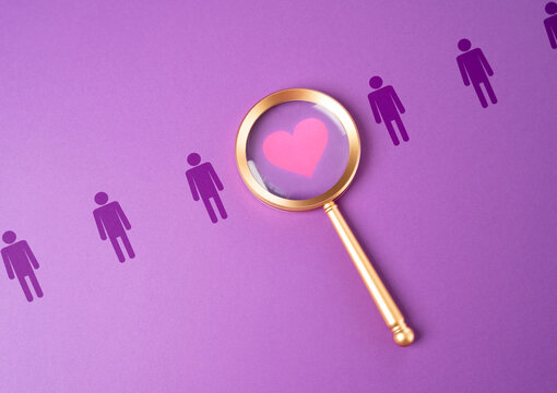 Search for love and dating. Magnifying glass finds the heart of love among the candidates. Matchmaking in online dating. Relationship building. Couple for February 14th.