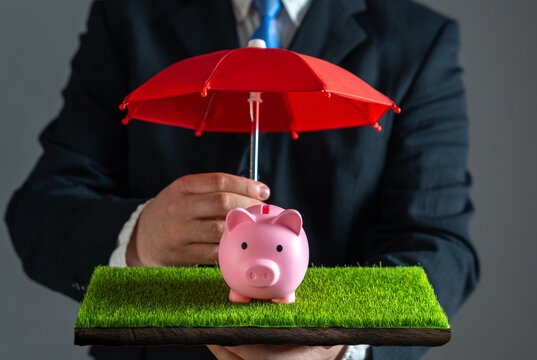 Businessman protects piggy bank with red umbrella. Savings insurance. Risk management, insurance coverage, investment safety, wealth preservation, and economic stability.