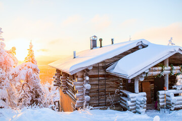 Snow-covered cabin at sunset