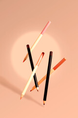 Elegant set of flying cosmetic pencils for eyes and brows in neutral tones on a soft beige background.