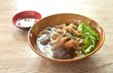 boiled braised beef meat and tendon couple organ in herb brown soup on bowl dipping spicy chili sauce 
