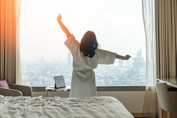 Hotel relaxation on lazy day with Asian woman waking up from good sleep on bed in weekend morning...