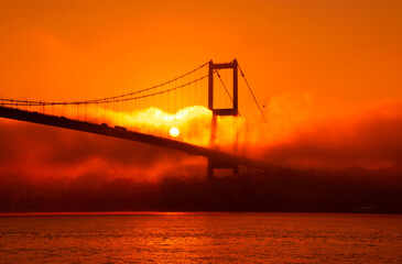 View of July 15 Martyrs Bridge (Bosphorus Bridge) with seagull and sunrise in fog clouds. A foggy view from the July 15 Martyrs Bridge in Ortakoy.
